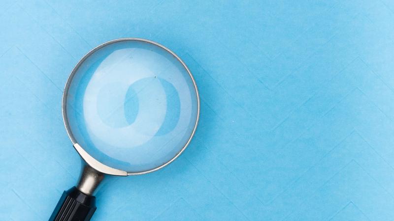 Magnifying glass reviewing printed documents