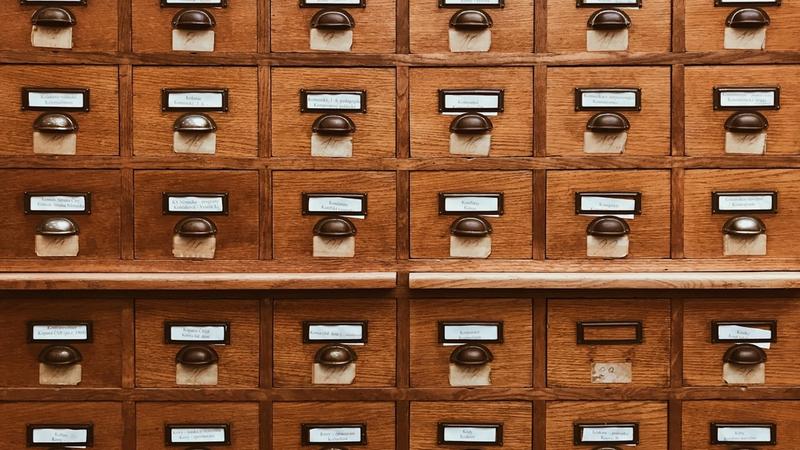 Rows of wooden index card drawers in a library catalogue, photo by Jan Antonin Kolar on Unsplash