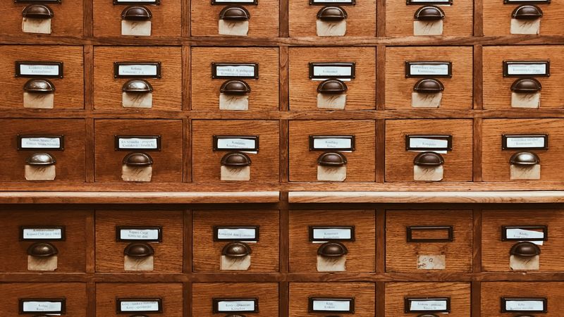 Rows of wooden index card drawers in a library catalogue, photo by Jan Antonin Kolar on Unsplash