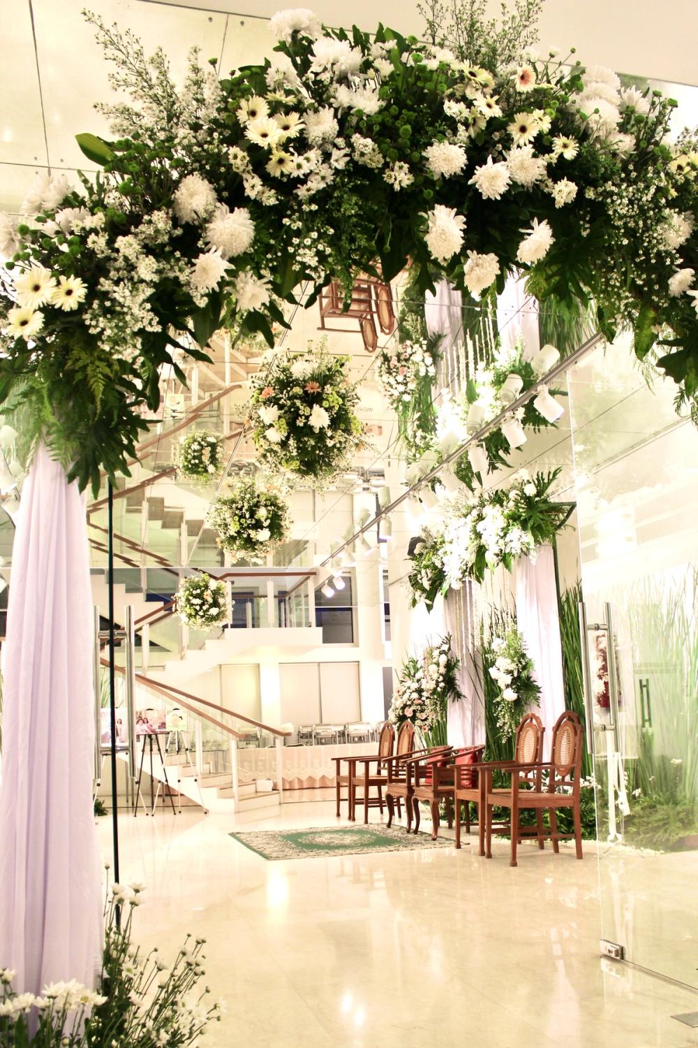 A white and green floral arch framing the Mawar Gallery staircase for a wedding