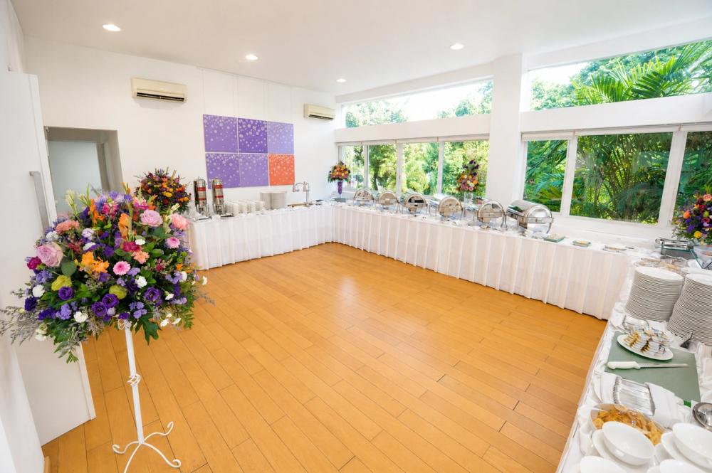 A buffet set along the windows of the Dahlia Room, with a floral arrangement by the entrance