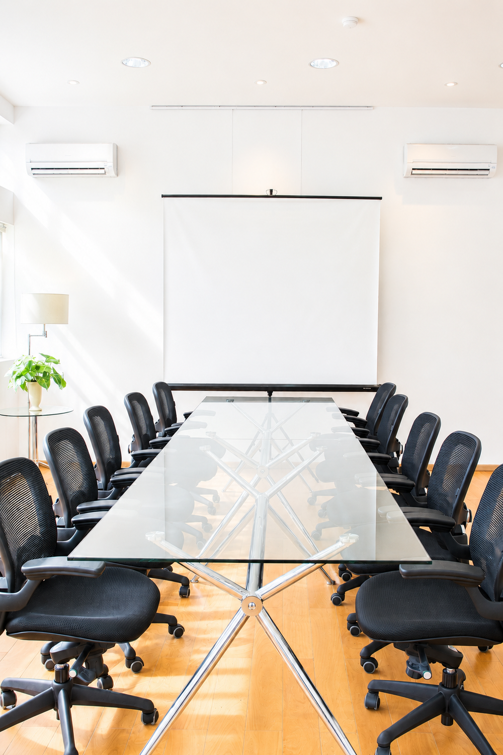 The Dahlia Room set up as a boardroom, with a glass table and a projector screen