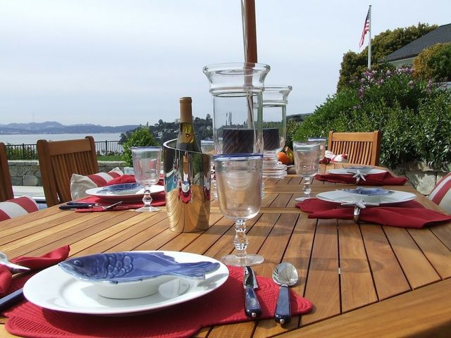 Gedekte tafel met borden en glazen op een houten terras aan het water