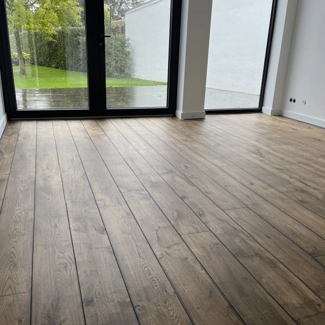 Grijs getinte eiken vloer bij de glazen pui, behandeld met Osmo Decorwas Transparant 3118, Granietgrijs