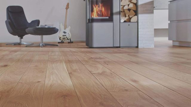 Woonkamer met lichte houten vloer, zwarte fauteuil en houtkachel