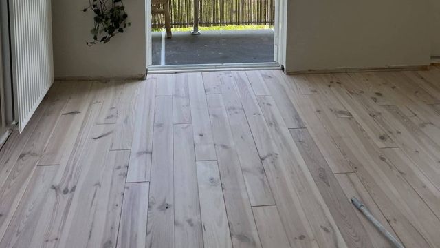 Lichtgrijze white-wash houten vloer in een hal met openslaande deuren