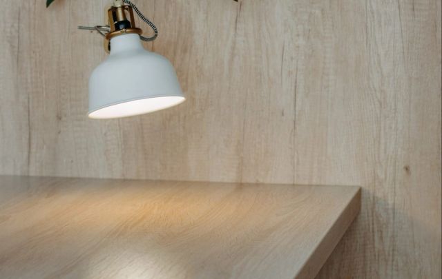 Witte hanglamp boven een licht houten plank tegen een lichte wand