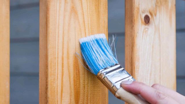 Hand die met een kwast verticale houten planken beitst