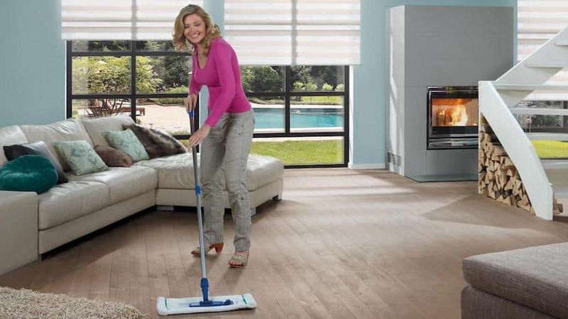 Vrouw maakt houten vloer schoon.