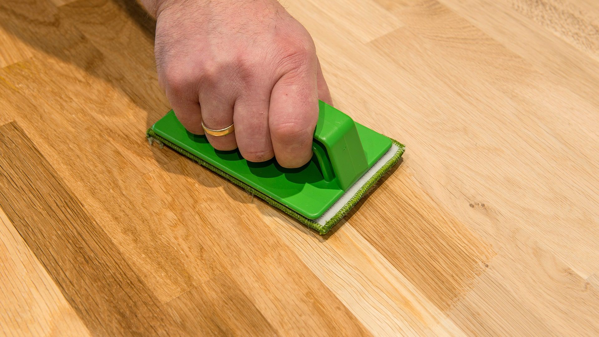 Persoon maakt houten vloer schoon.