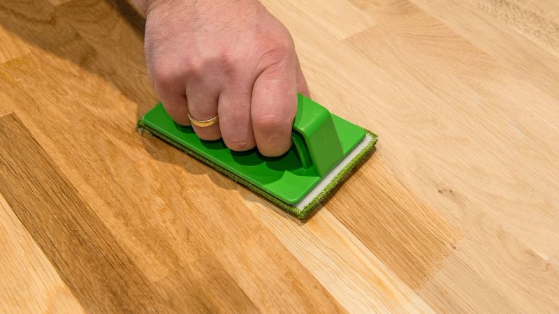 Persoon maakt houten vloer schoon.