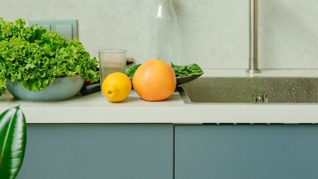 Groen keukenblok met licht werkblad, groenten en fruit erop