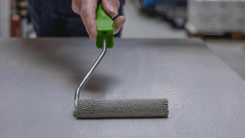 Persoon brengt verf met roller aan