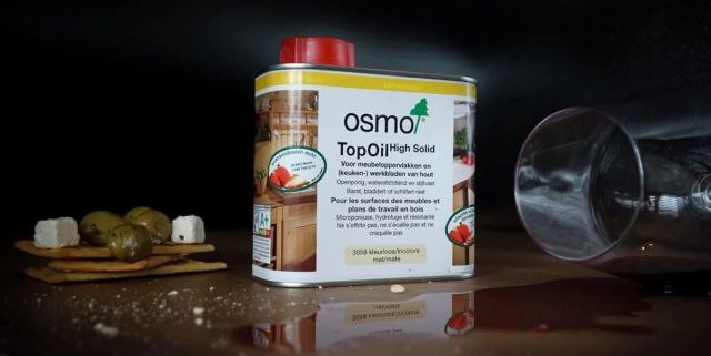 Blik Osmo TopOil met borrelplank en glas op een donkere achtergrond
