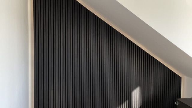 Zwarte houten wandpanelen langs een schuine wand