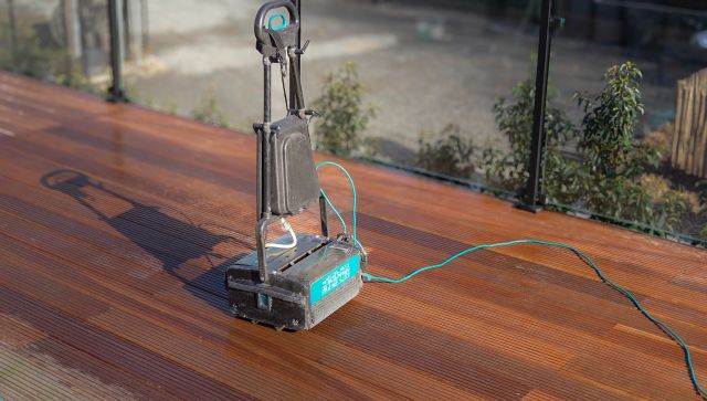Borstelmachine die een houten terras reinigt