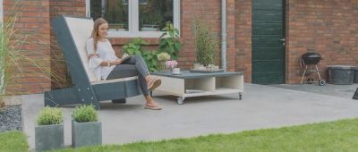 Vrouw zit op stoel in de tuin.