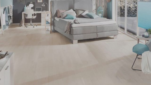Slaapkamer met lichte houten vloer, bed en blauwe stoel