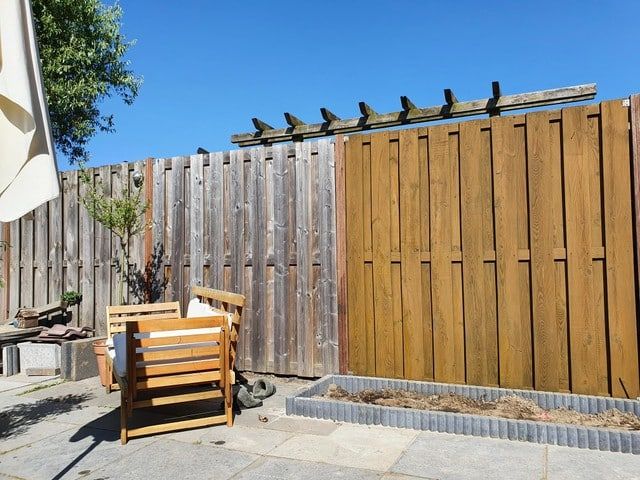 Houten schutting in de tuin, deels behandeld
