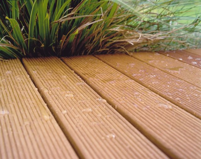 Natte houten vlonderplanken met siergras ernaast