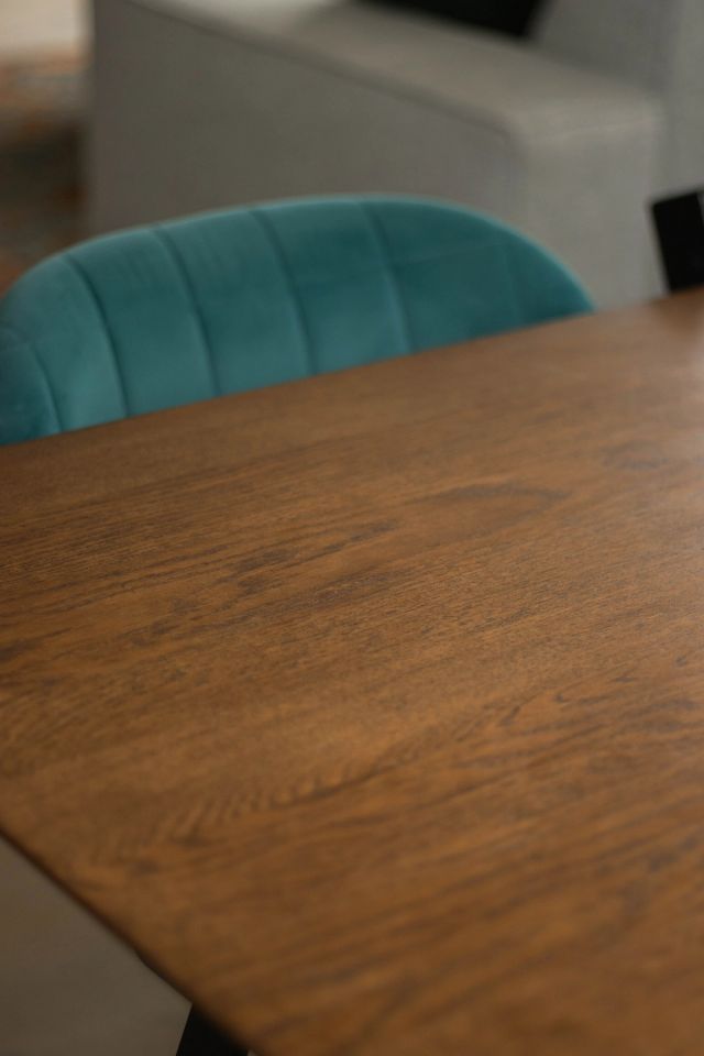 Hoek van een eikenhouten tafel met een groene stoel
