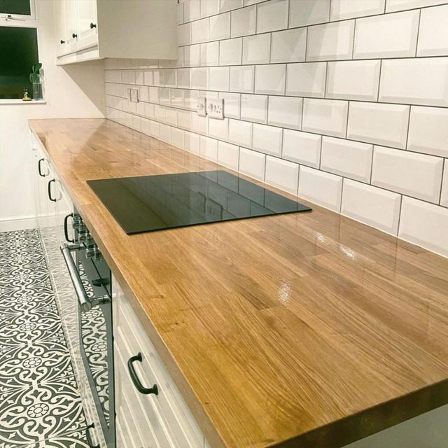 Keuken met een houten werkblad en witte tegelwand