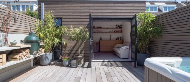 Tuin met houten schutting, buitenkeuken en overkapping