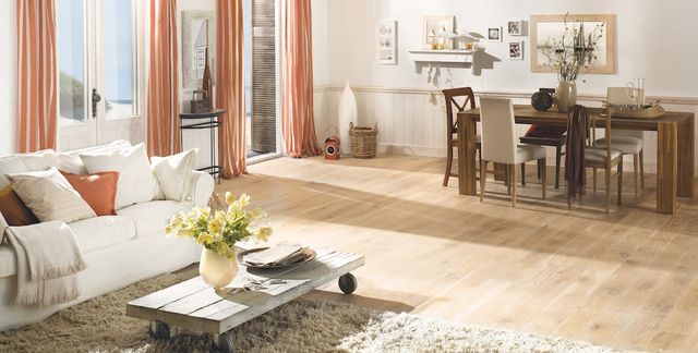 Woonkamer met lichte houten vloer, bank en eettafel