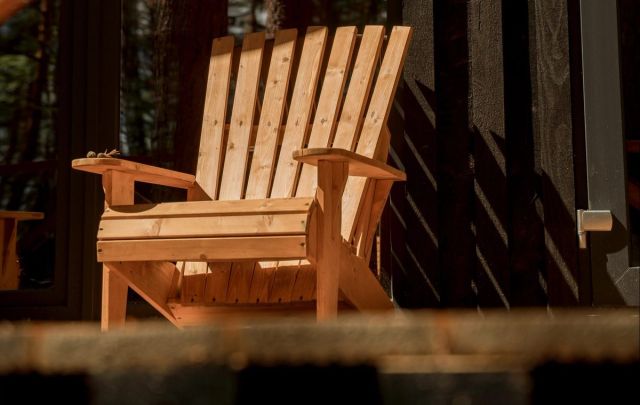 Houten Adirondack-tuinstoel bij een schutting in de avondzon
