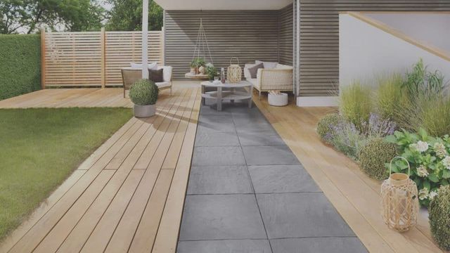 Tuin met houten vlonderpad, tegels en een overkapping