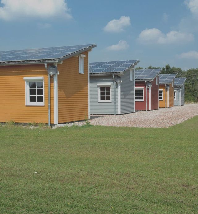 Geel en rood geschilderde houten woningen aan een grasveld