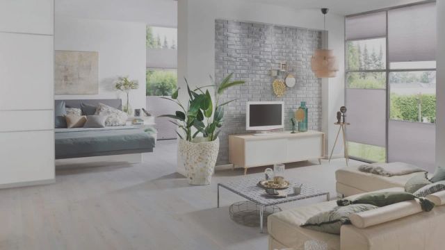 Woonkamer met lichtgrijze houten vloer, bank en tv-meubel