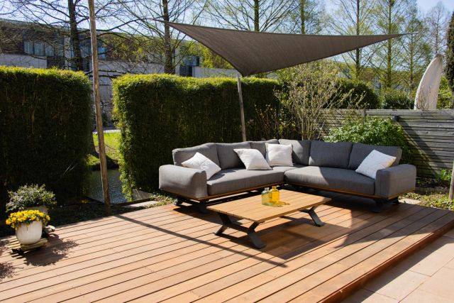 Vlonderterras met loungeset en schaduwdoek in de tuin