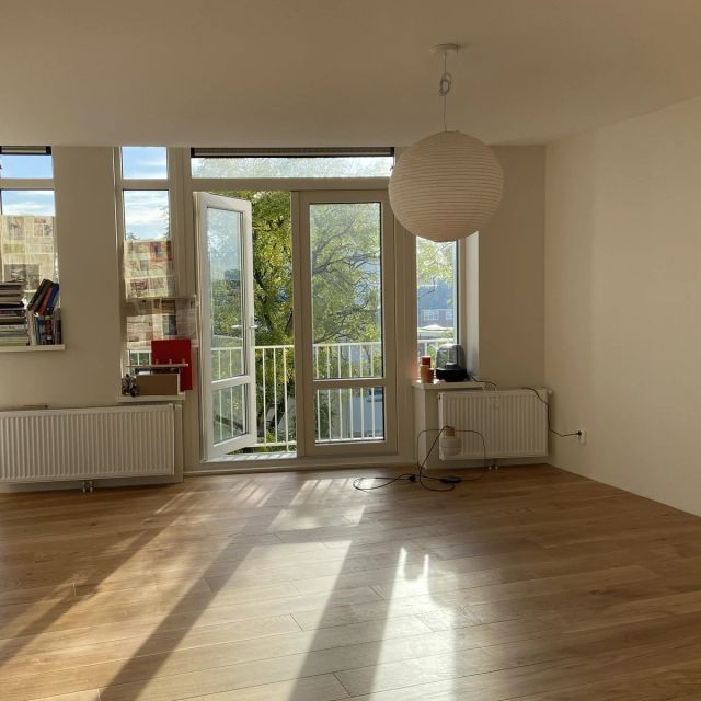 Eiken vloer in een zonnige, lege kamer met balkondeuren, behandeld met Osmo Hardwaxolie Original 3065, Kleurloos semi-mat