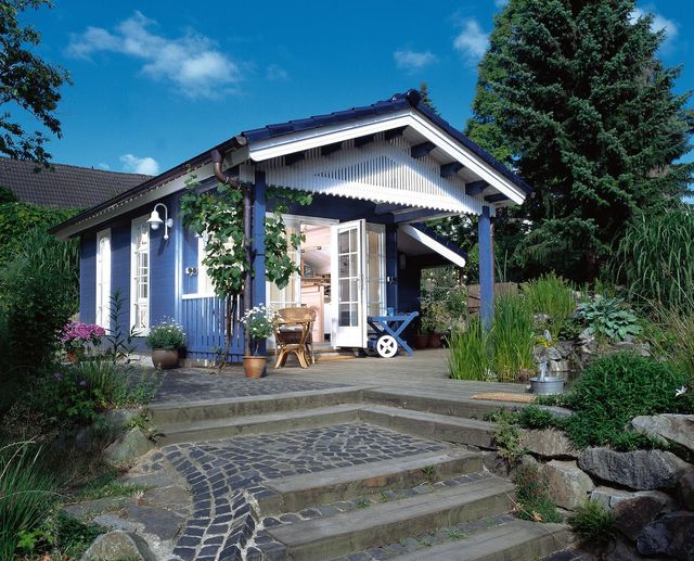 Blauw geverfd tuinhuis met overkapping in een tuin