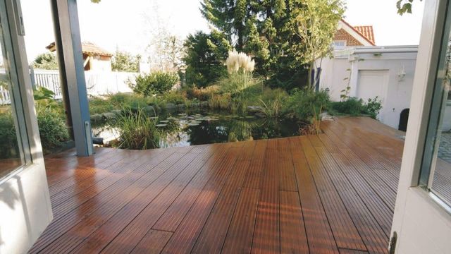 Houten vlonderterras bij een vijver, gezien vanuit huis
