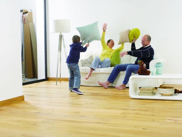 Gezin dat met kussens speelt in een woonkamer met beukenhouten vloer
