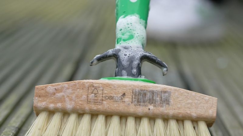 An Osmo brush cleaning a patio