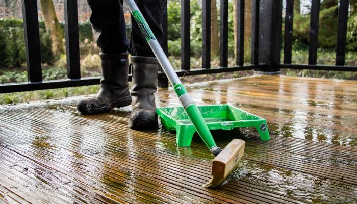 Person coating wooden decking