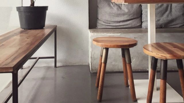 Houten krukken en een bank tegen een betonlook wand
