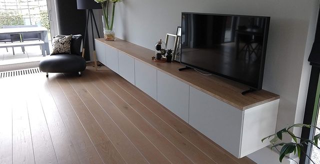 Houten tv-meubel met witte kastdeuren in een woonkamer