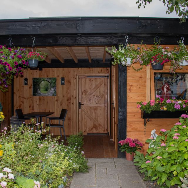 Douglas overkapping met tuinhuis tussen de bloemen, behandeld met Osmo UV-Beschermingsolie 420, Kleurloos