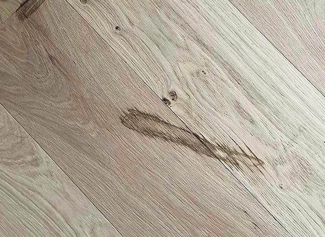 Close-up van een lichte houten vloer met een donkere vlek