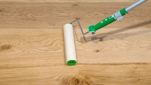 Roller die olie aanbrengt op een eikenhouten vloer