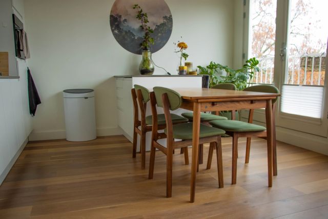 Eetkamer met houten vloer, tafel en stoelen bij het raam