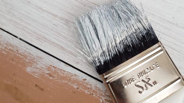 Kwast met witte verf op een houten oppervlak