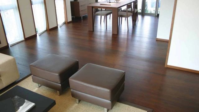 Interieur met donkerbruine houten vloer en lichte poefs