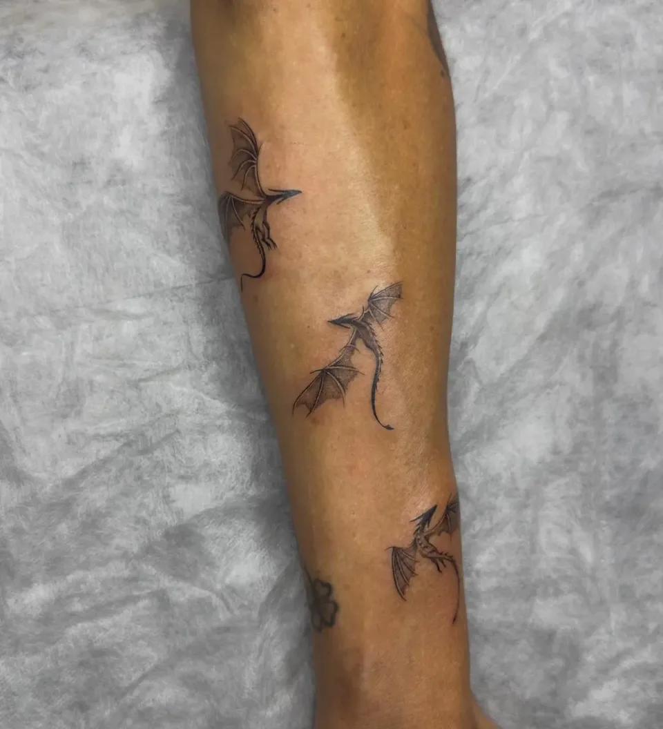 Three small fine line flying dragons tattooed on a forearm, minimalist black ink tattoo style done by a professional artist in Budva Montenegro.