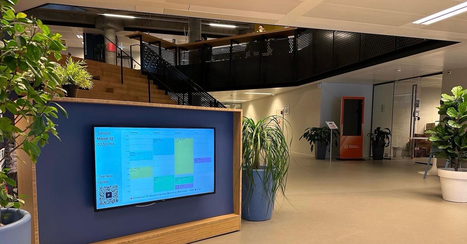 A lobby with the day's schedule displayed on a television mounted on a reception desk
