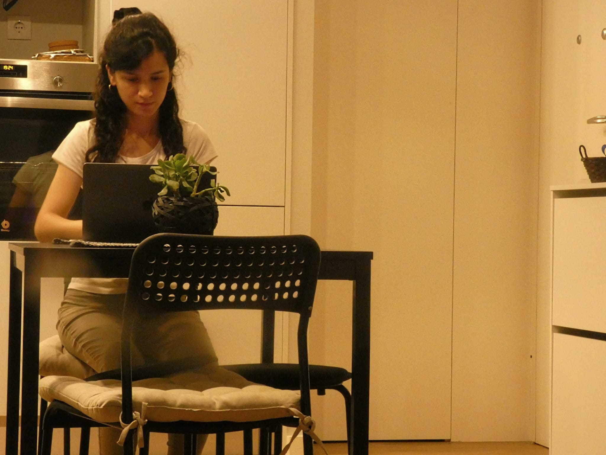 woman sitting on a kitchen table working on her laptop